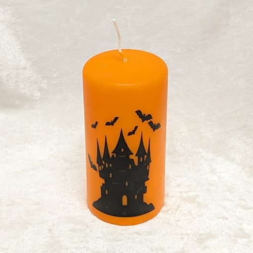 Orangefarbene Blockkerze mit gruseligem Schloss und Fledermaus für Halloween