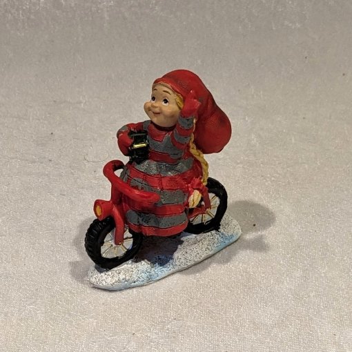 Kleines Elfenmädchen, das auf einem roten Fahrrad fährt und winkt